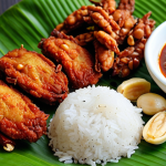 **A vibrant and appetizing close-up shot of Nasi Lemak on a banana leaf plate. The dish features fluffy coconut rice, a fiery red sambal, crispy fried anchovies, roasted peanuts, slices of fresh cucumber, and a perfectly cooked fried chicken. The composition emphasizes the textures and colors of the ingredients, showcasing the culinary masterpiece.**